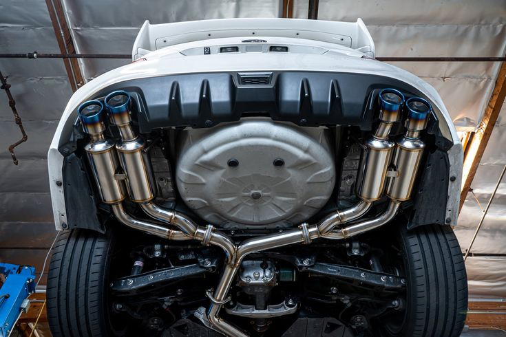 Detailed view of a car's exhaust pipes, emphasizing their structure and connection to the vehicle's undercarriage.<br />