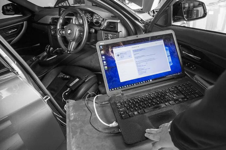 A Guy Using Laptop Inside A Car To Tune Ecu - Strike7 Performance Inside a car, an individual operates a laptop for car diagnostics.